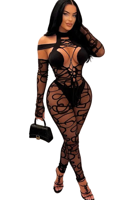 Woman wearing a black mesh outfit with long sleeves against a white wall.