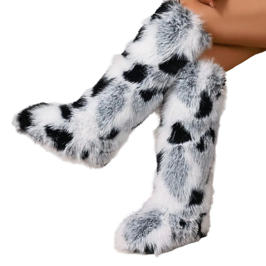 Black and white fur boots worn by a person sitting on a beige chair.